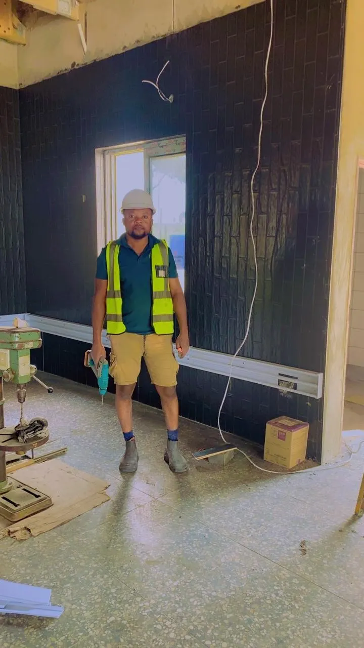 Electrician next to newly installed wall trunking in an office